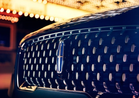 The Corsair Grand Touring grille shows floating chrome ovals that catch the glowing light of a theater marquee and frame the distinctive Lincoln Star | Mark Ficken Lincoln in Charlotte NC