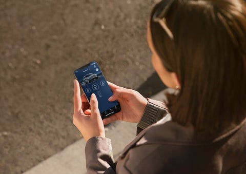 A person is shown interacting with a smartphone to connect to a Lincoln vehicle via the Lincoln Way® App. | Mark Ficken Lincoln in Charlotte NC