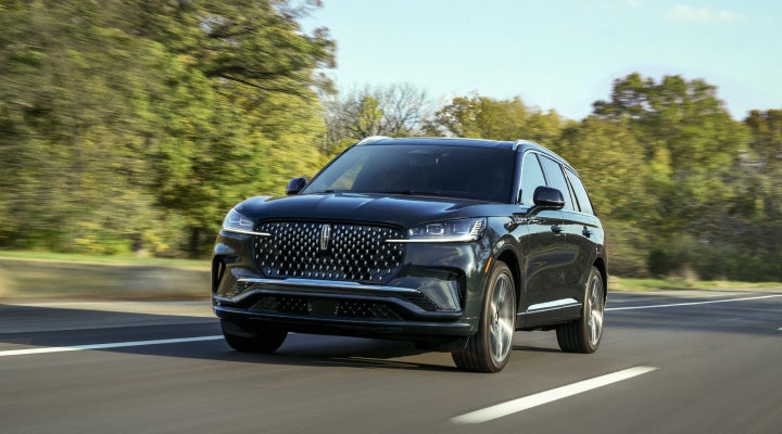 A 2026 Lincoln Black Label™ Aviator® SUV is being driven down a road lined with trees. | Mark Ficken Lincoln in Charlotte NC